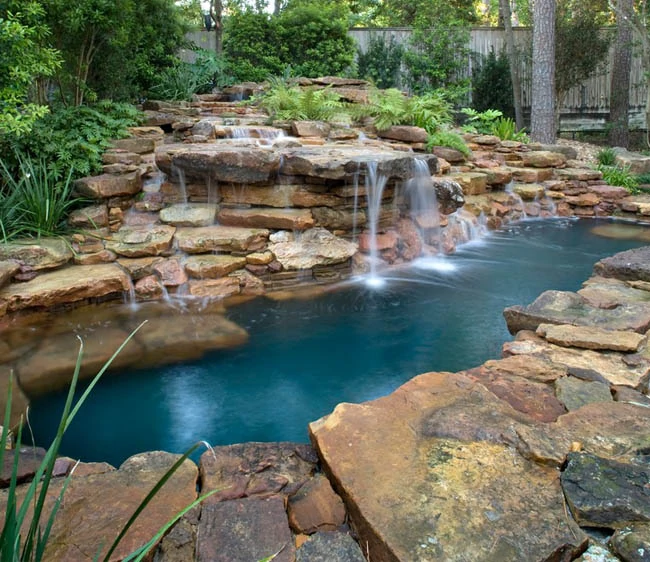 Natural swimming pool with rock waterfall design